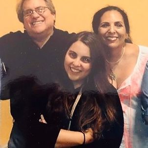 Sharon Lyn with her husband and daughter smiling for a picture.